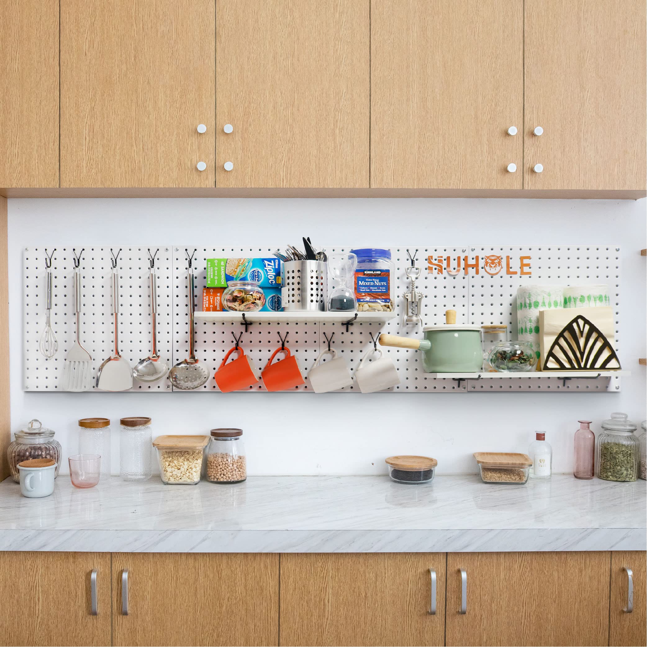 This image depicts an organized kitchen pantry or storage area utilizing a pegboard system with Huhole-style hooks. The pegboard is mounted above a counter or shelf, providing ample space to neatly display and store a variety of kitchen essentials.