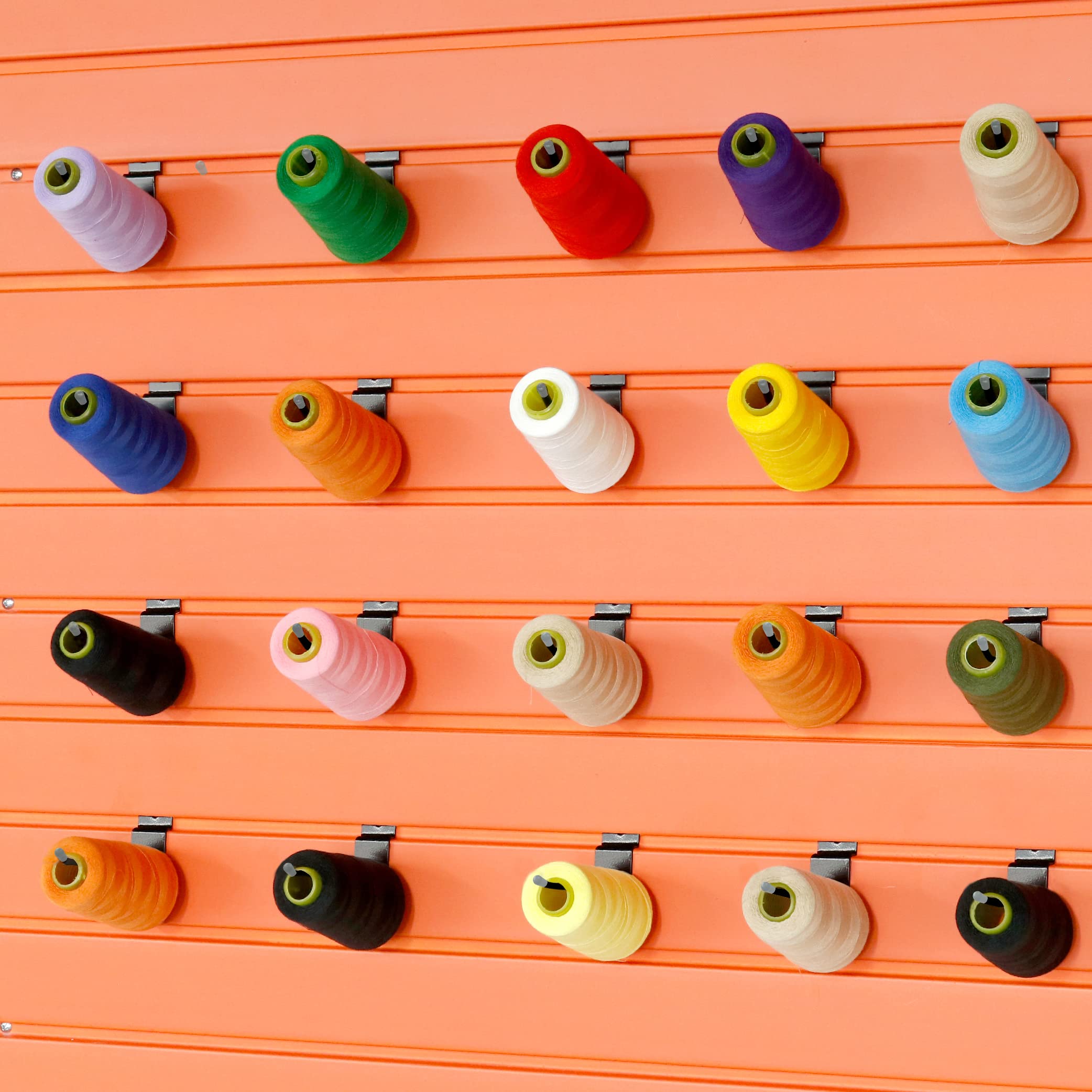 This image showcases a vibrant and organized display of colorful spools of thread or yarn mounted on a slatwall. 